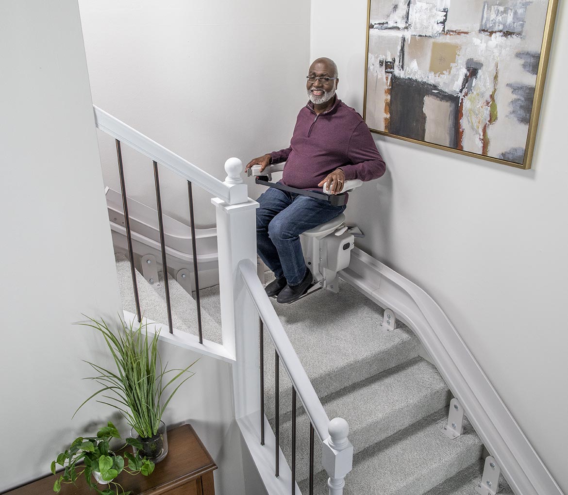 Man on a stairlift in home installed from a company Supporting Veterans with Reliable Accessibility Solutions